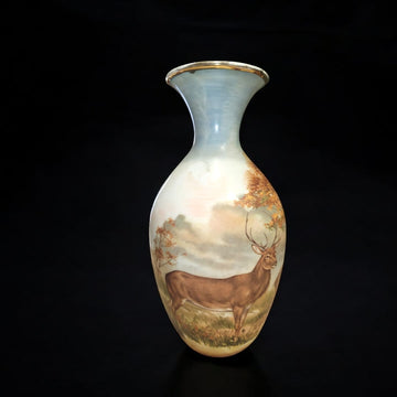 Jarrón de porcelana decorado con ciervo en paisaje natural otoñal, detalles pintados a mano y filo dorado.