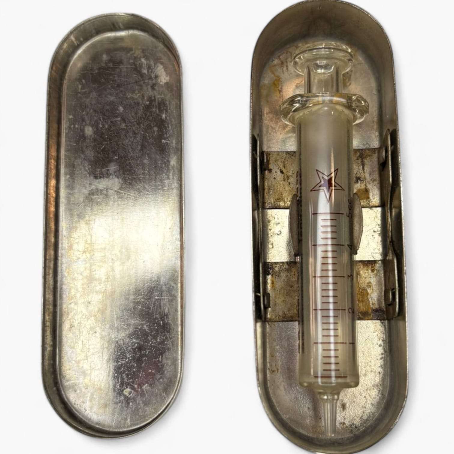 Jeringa antigua de cristal dentro de su estuche metálico abierto.