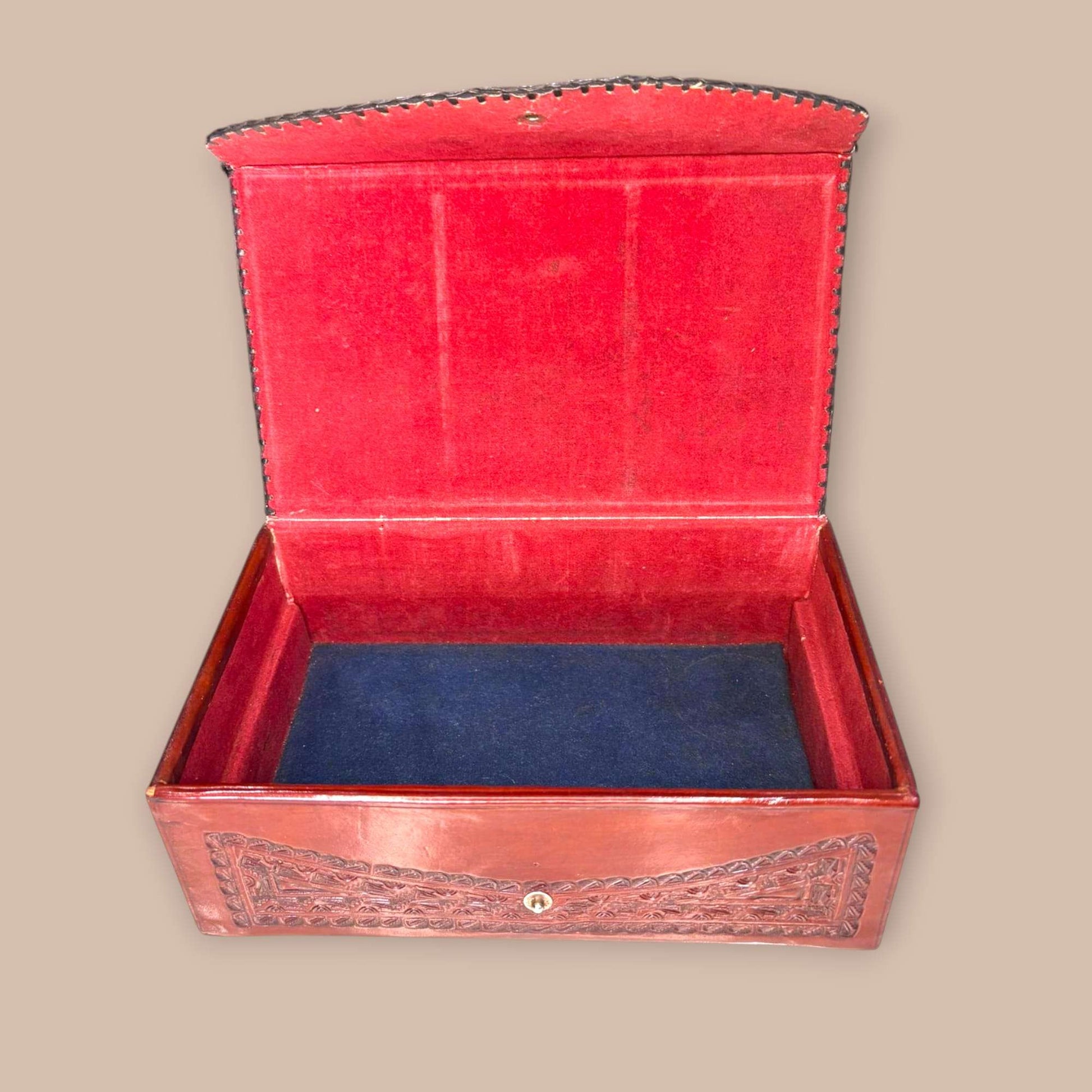 Joyero de cuero con relieves tipo calendario azteca abierto, interior forrado en terciopelo rojo y base azul. Ideal para decoración y colección.