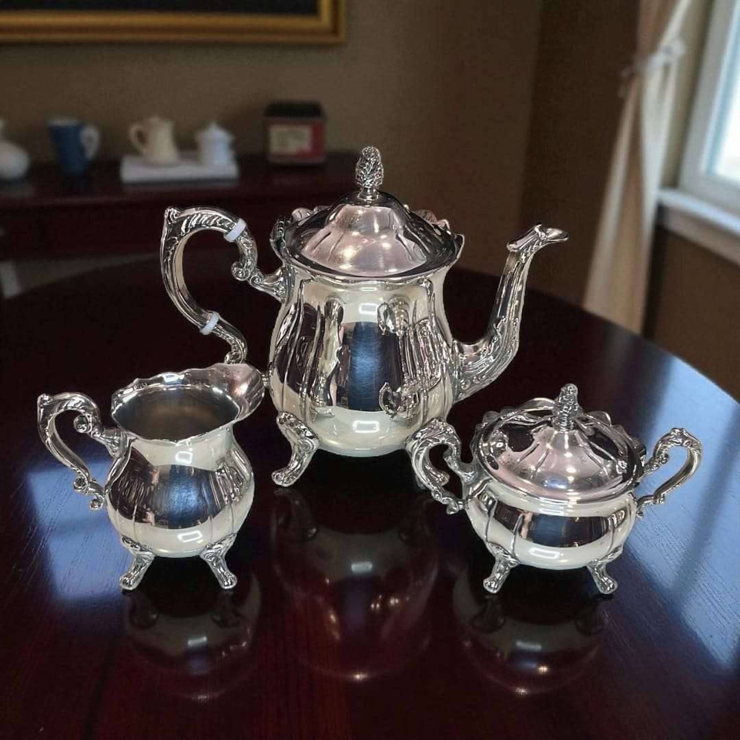 Juego de café de estilo clásico con asas ornamentadas y tapa decorativa.