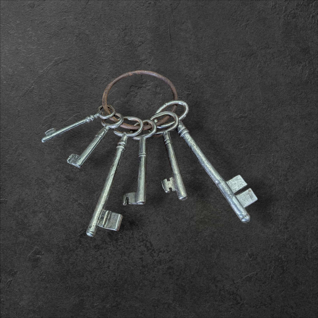 Llaves de la Suerte: un símbolo que atrae lo bueno, juego decorativo de llaves antiguas en anillo metálico sobre fondo oscuro. Ideal para decoración vintage con estilo histórico.