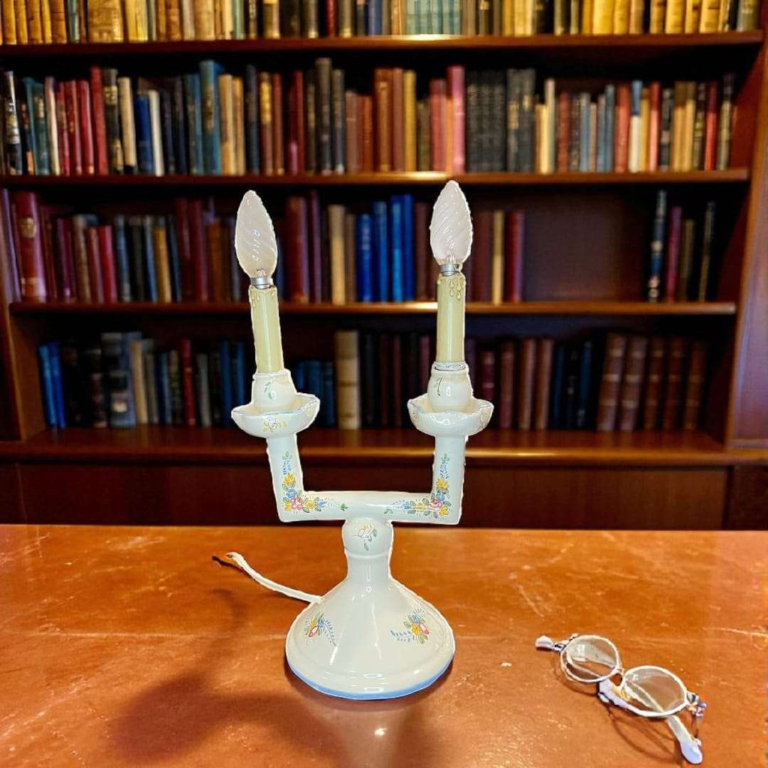 Lámpara de mesa de porcelana de Manises encendida en biblioteca clásica.