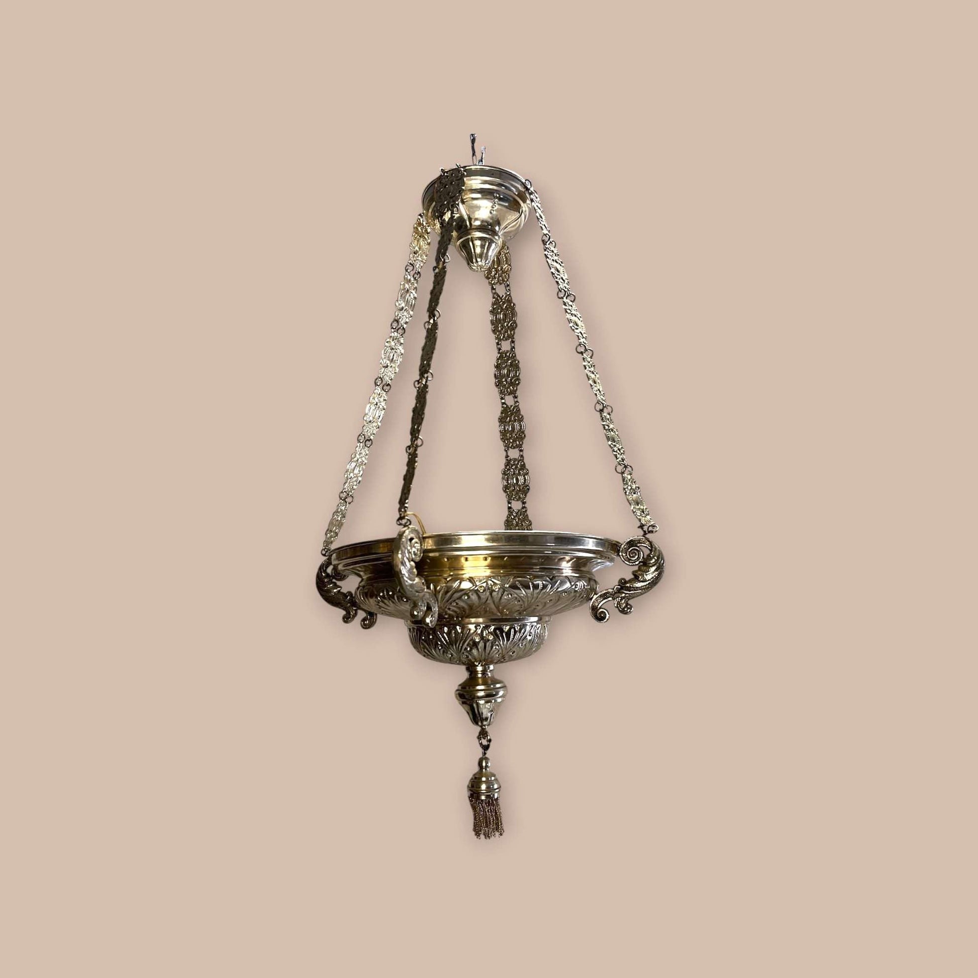 Lámpara votiva de metal plateado colgante con cadenas ornamentales.