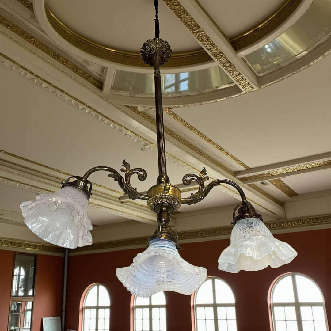 Lámpara de techo de metal con tres brazos en salón clásico.