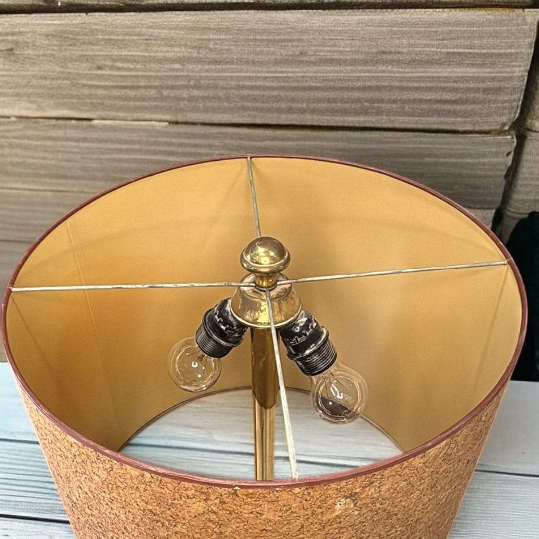  Elaborada en metal dorado texturado, esta lámpara destaca por su base torneada con líneas concéntricas y un cuerpo estilizado que aporta verticalidad y presencia.