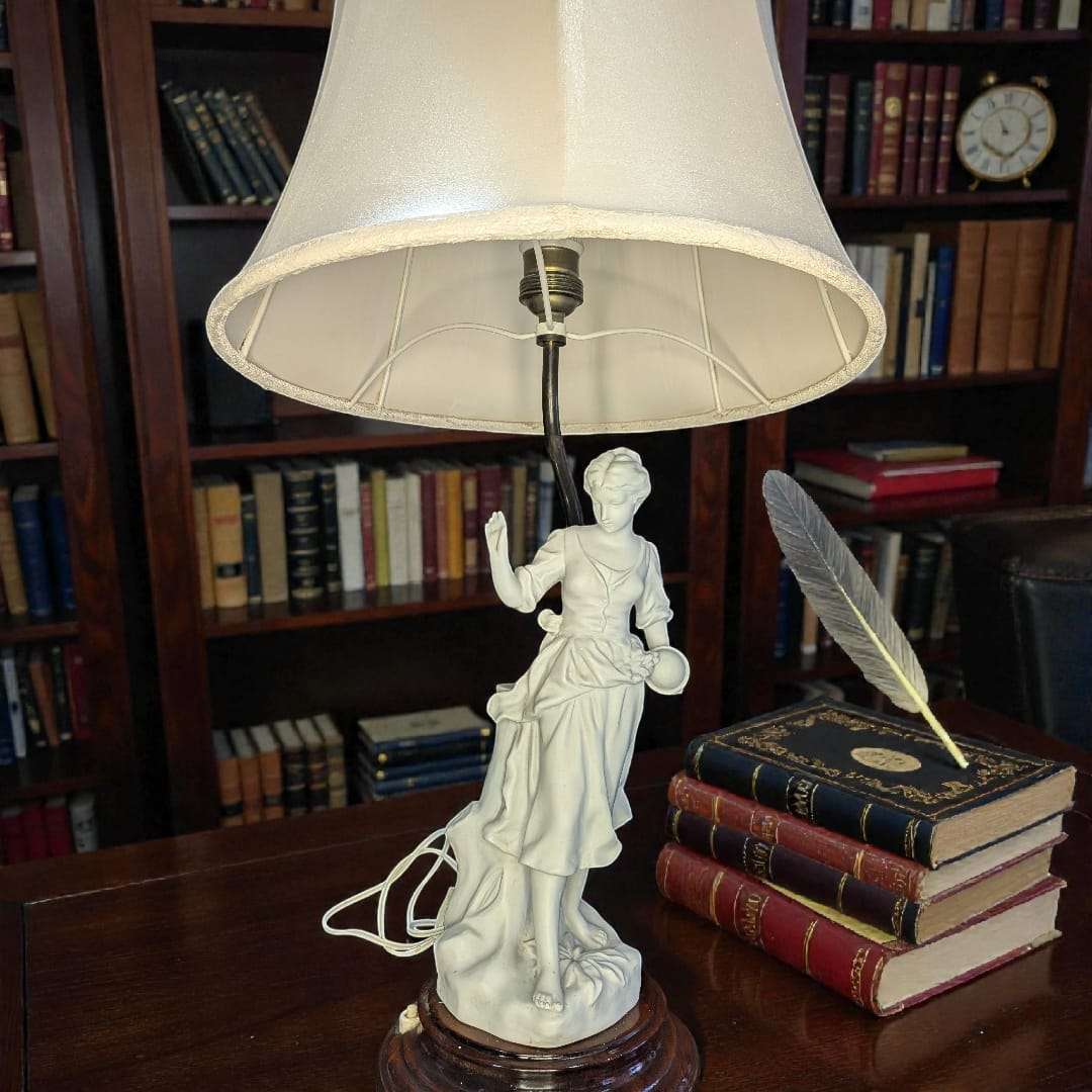 Lámpara de sobremesa con figura de porcelana biscuit de mujer sobre base de madera y pantalla blanca, ideal para decoración clásica de interiores.