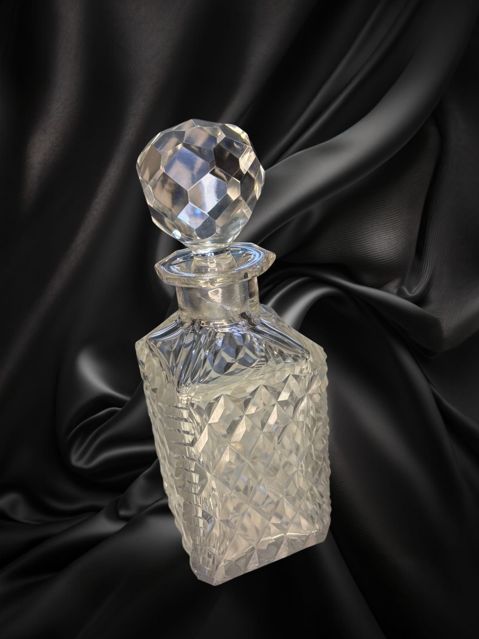 Licorera de cristal con cuello de plata y tapón facetado, estilo vintage. Perfecta para decoración de bares o salones elegantes.