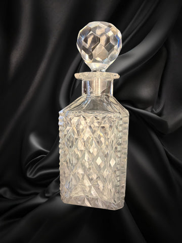 Licorera de cristal con cuello de plata, diseño tallado con tapón facetado. Elegancia clásica para decoración de interiores sofisticados.