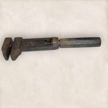 Llave inglesa antigua ajustable vista lateral con pátina metálica.