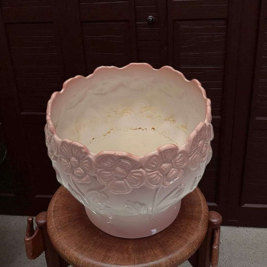 Macetero de porcelana con relieve floral en tonos rosados.