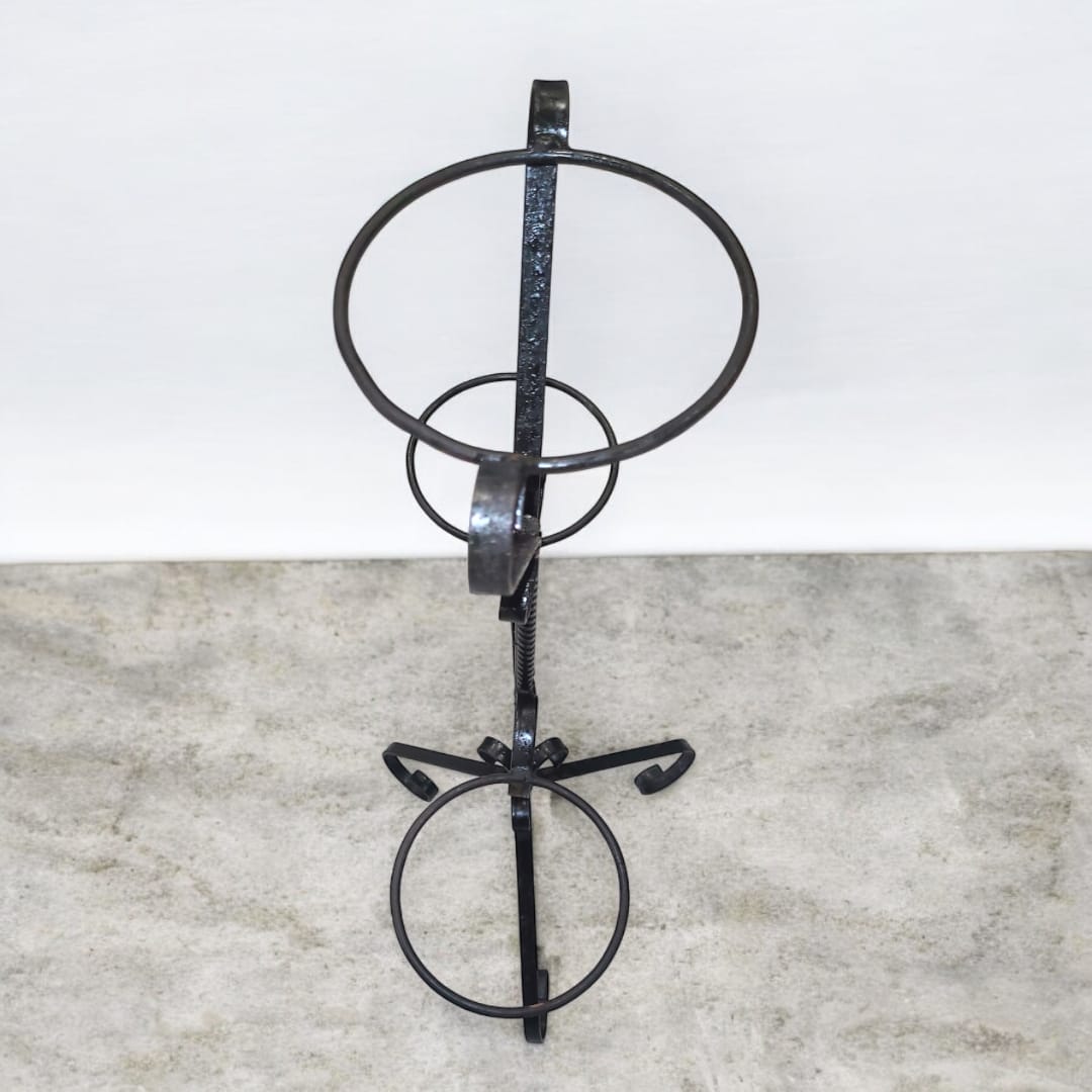 Macetero de hierro forjado visto desde arriba, mostrando la disposición circular de los soportes para macetas.