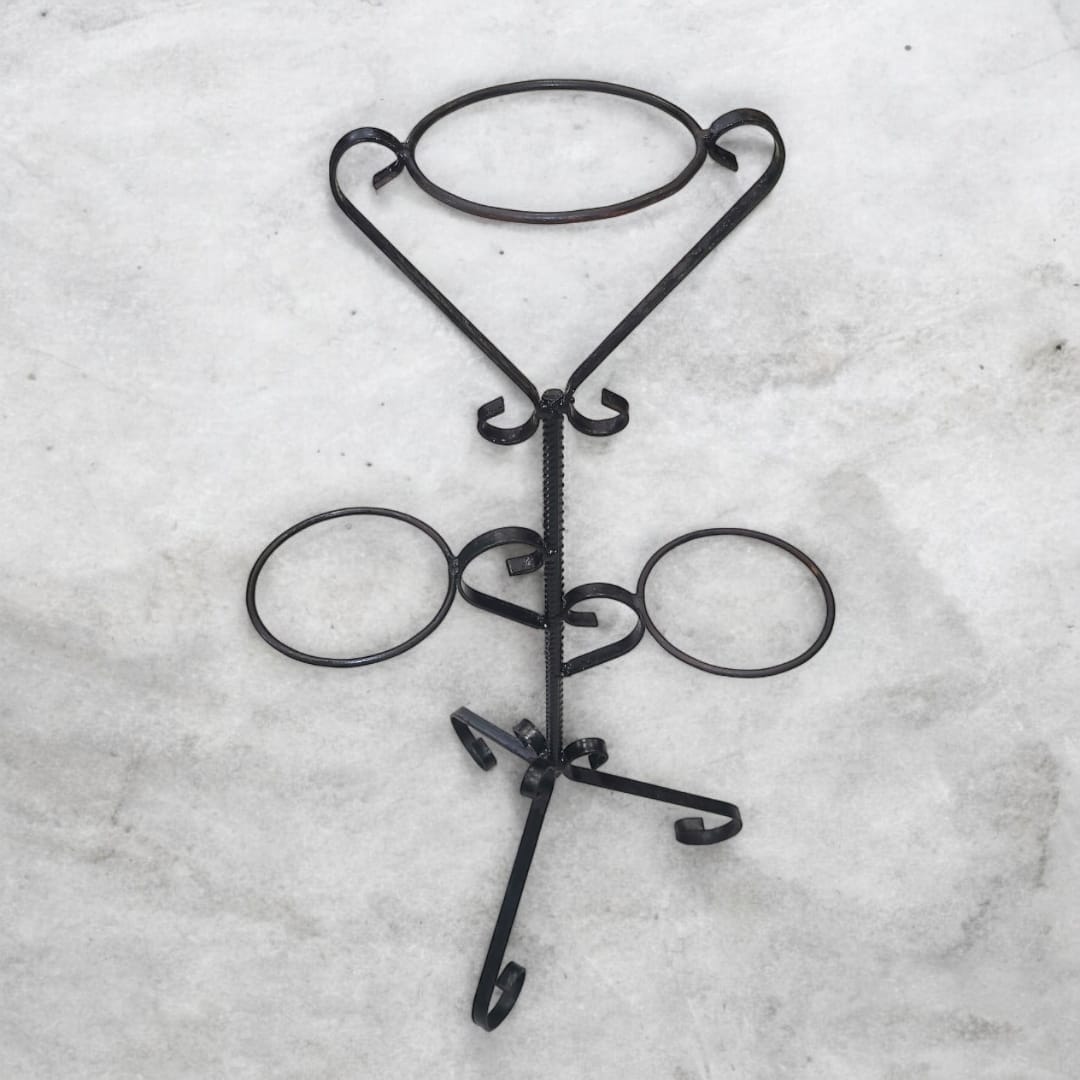 Macetero de hierro negro colocado sobre una superficie blanca, destacando su acabado elegante y resistente.