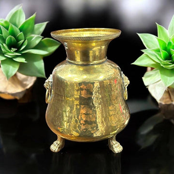 Macetero metálico vintage con patas en forma de garra y asas decorativas de león, ideal para decoración elegante de interiores.