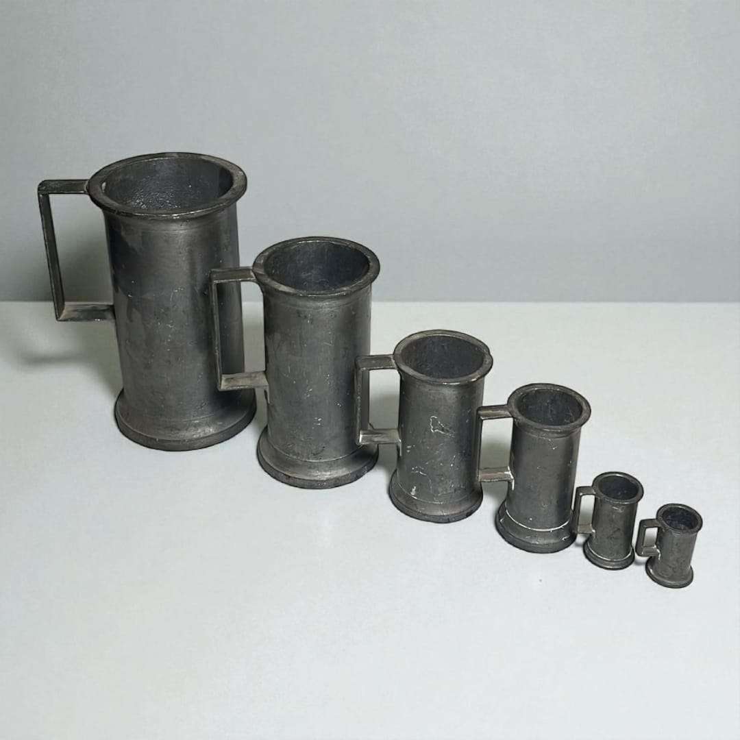 Juego de medidas de líquidos en estaño antiguo ordenadas de mayor a menor.