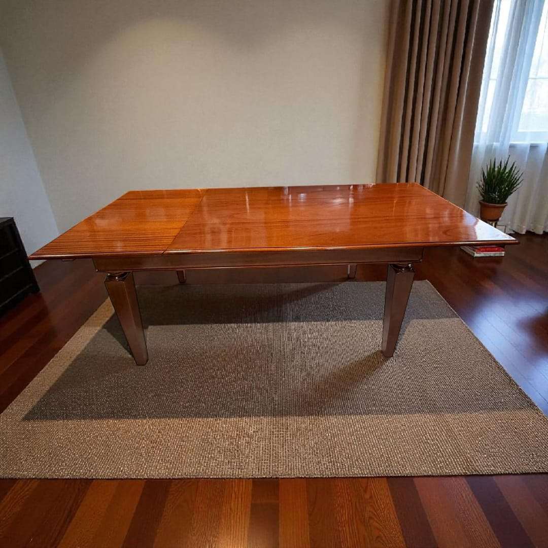 Mesa de comedor de caoba extensible con superficie brillante.