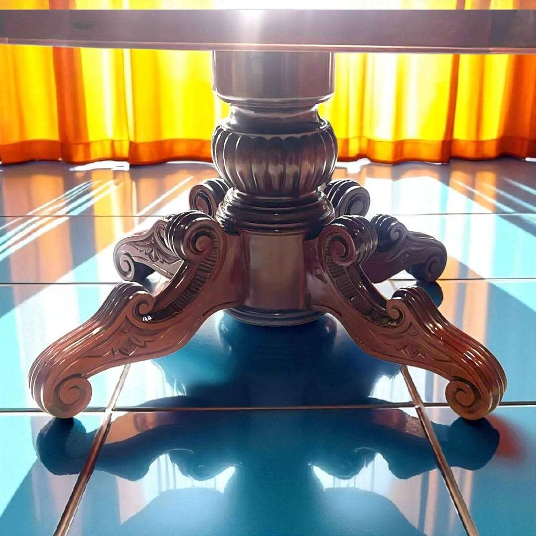Detalle de la base tallada a mano de mesa comedor de caoba antigua, con diseño ornamental robusto y acabado artesanal de alta calidad.