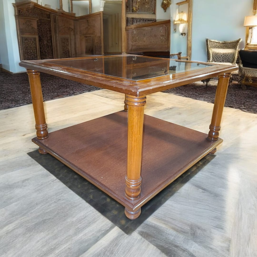 Mesa baja de madera de caoba con tapa de cristal elegante y patas torneadas, ideal para salas clásicas. Incluye estante inferior para almacenamiento.