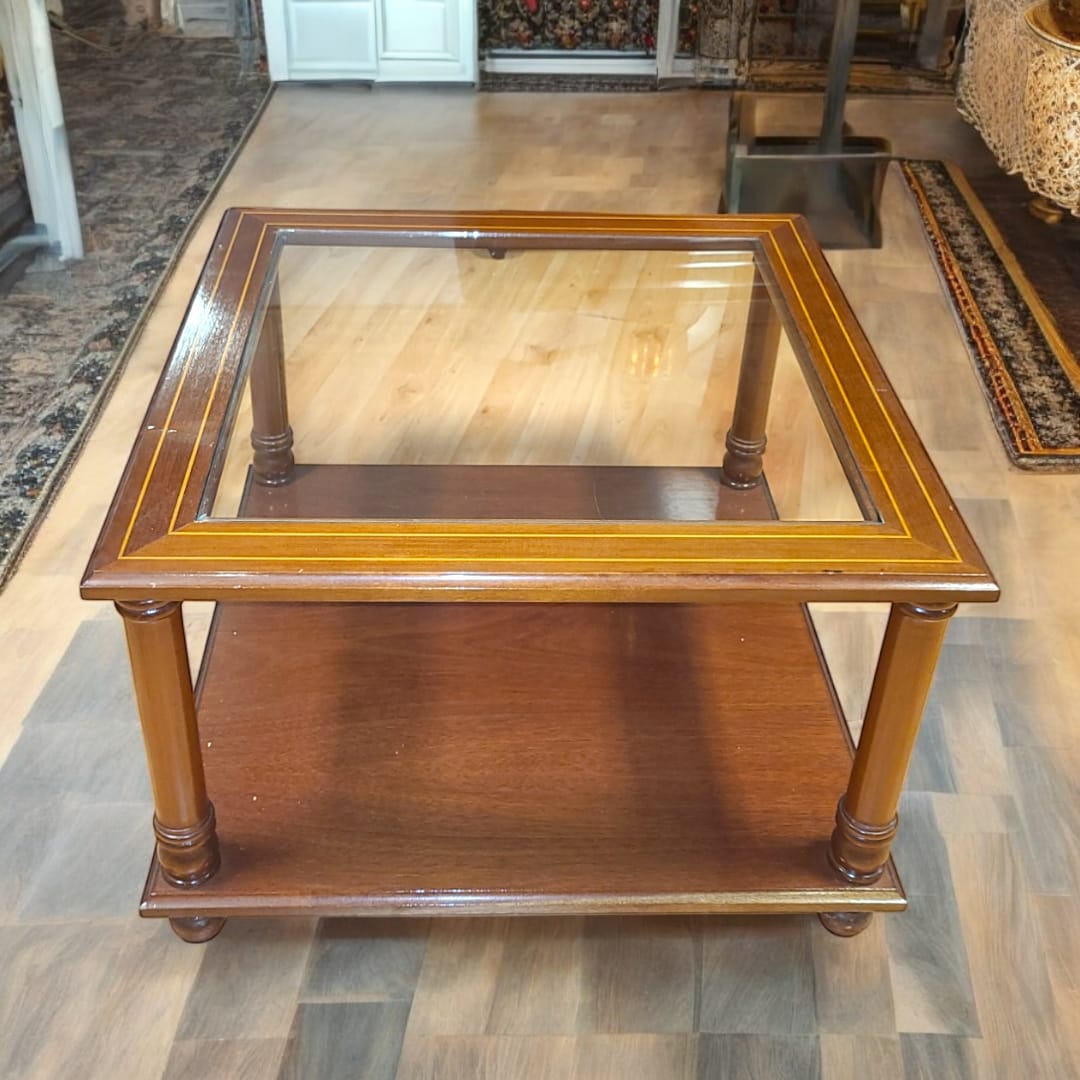 Mesa baja de madera de caoba con tapa de cristal elegante y patas torneadas, ideal para salas clásicas. Incluye estante inferior para almacenamiento.