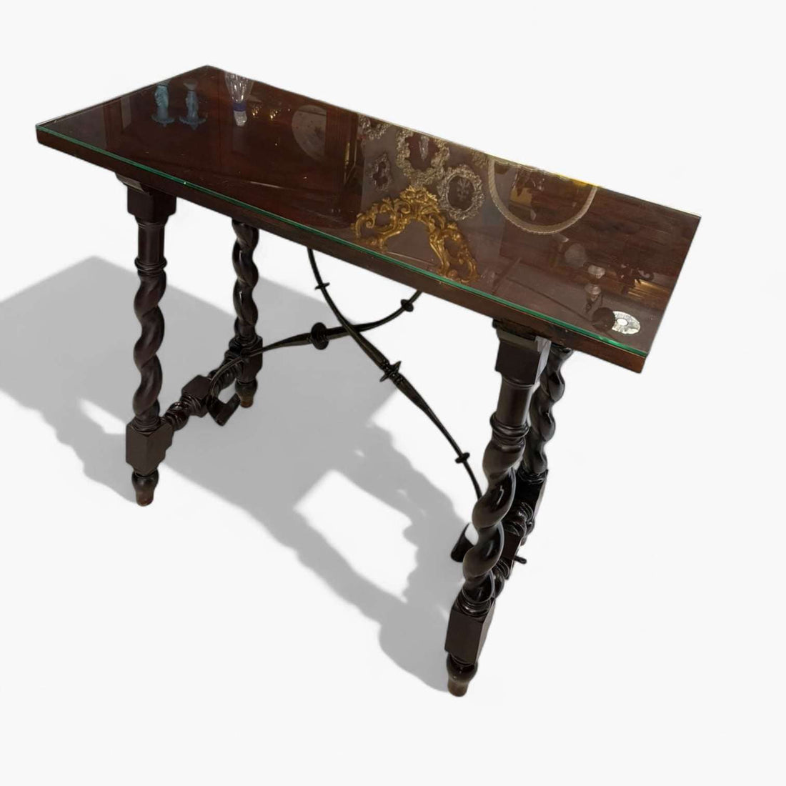 La mesa castellana de caoba con tapa de cristal es una pieza que reúne historia, nobleza y funcionalidad en un solo mueble. 