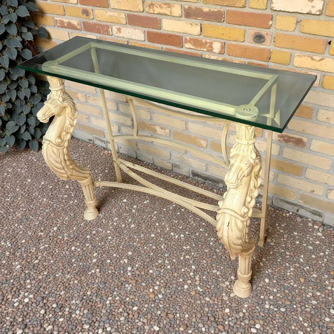 Esta Mesa con patas de caballo y tapa de cristal ha sido concebida como mesa consola decorativa, ideal para recibidores, pasillos amplios, salones elegantes o espacios comerciales con personalidad.