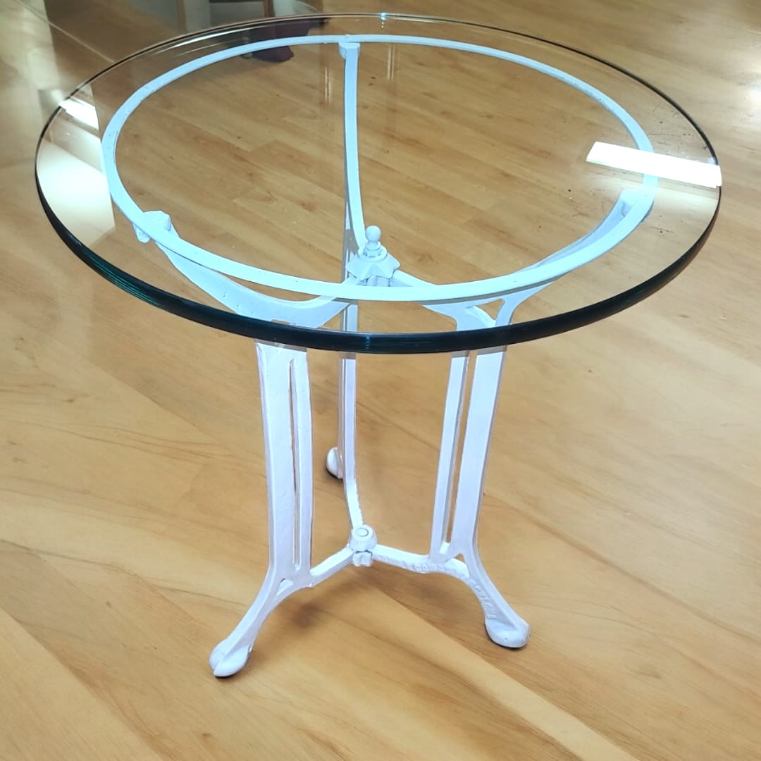 Vista frontal de la mesa: "Mesa de hierro forjado con tapa de cristal templado. Un diseño atemporal y elegante."