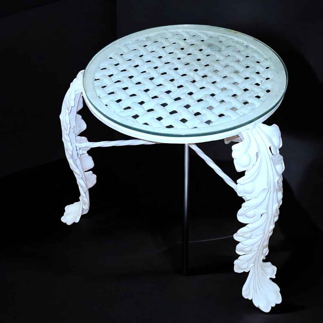 Vista frontal de la mesa: "Mesa de jardín en hierro forjado con tapa de cristal. Diseño clásico y resistente para exteriores elegantes."