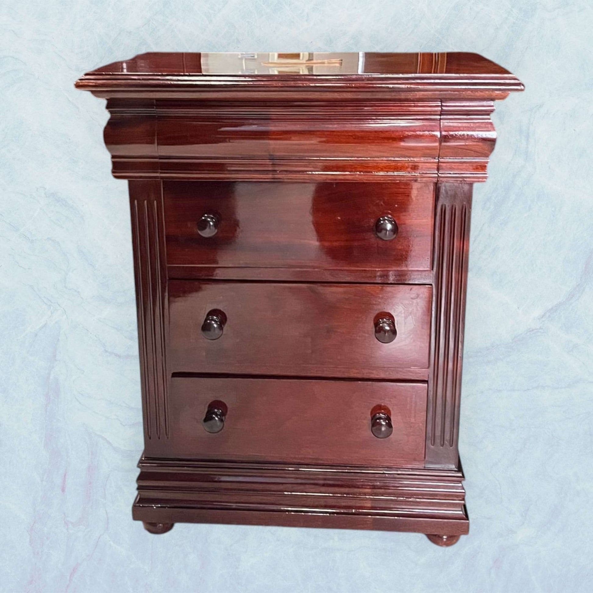 Mesita de noche de caoba con acabado brillante, tres cajones y diseño clásico. Ideal para decoración elegante en dormitorios.