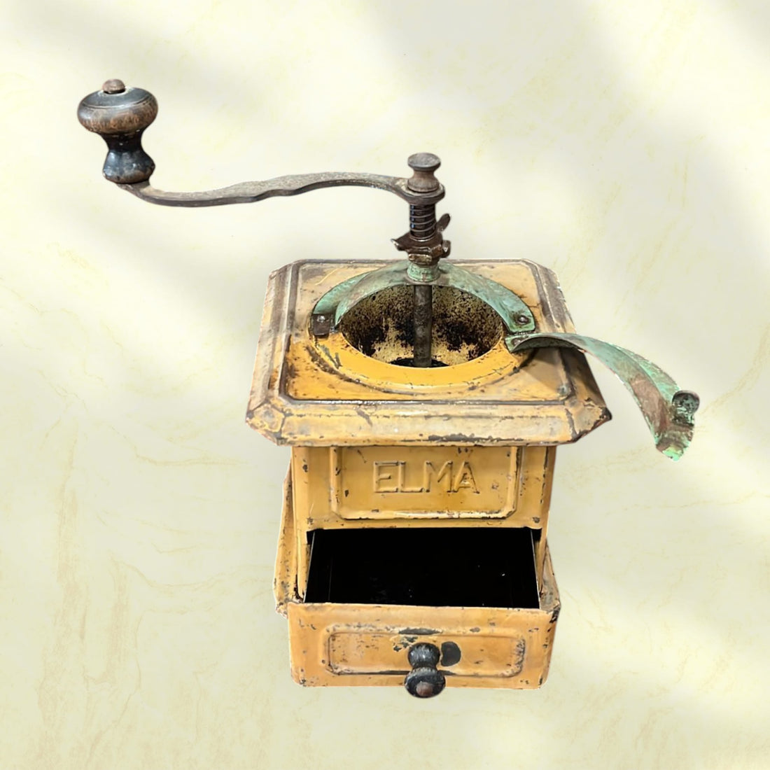 Molinillo de café Elma antiguo de hierro fundido, pieza única con acabado envejecido en color amarillo y detalles en verde oxidado. Ideal para decoración vintage en cocina o sala.