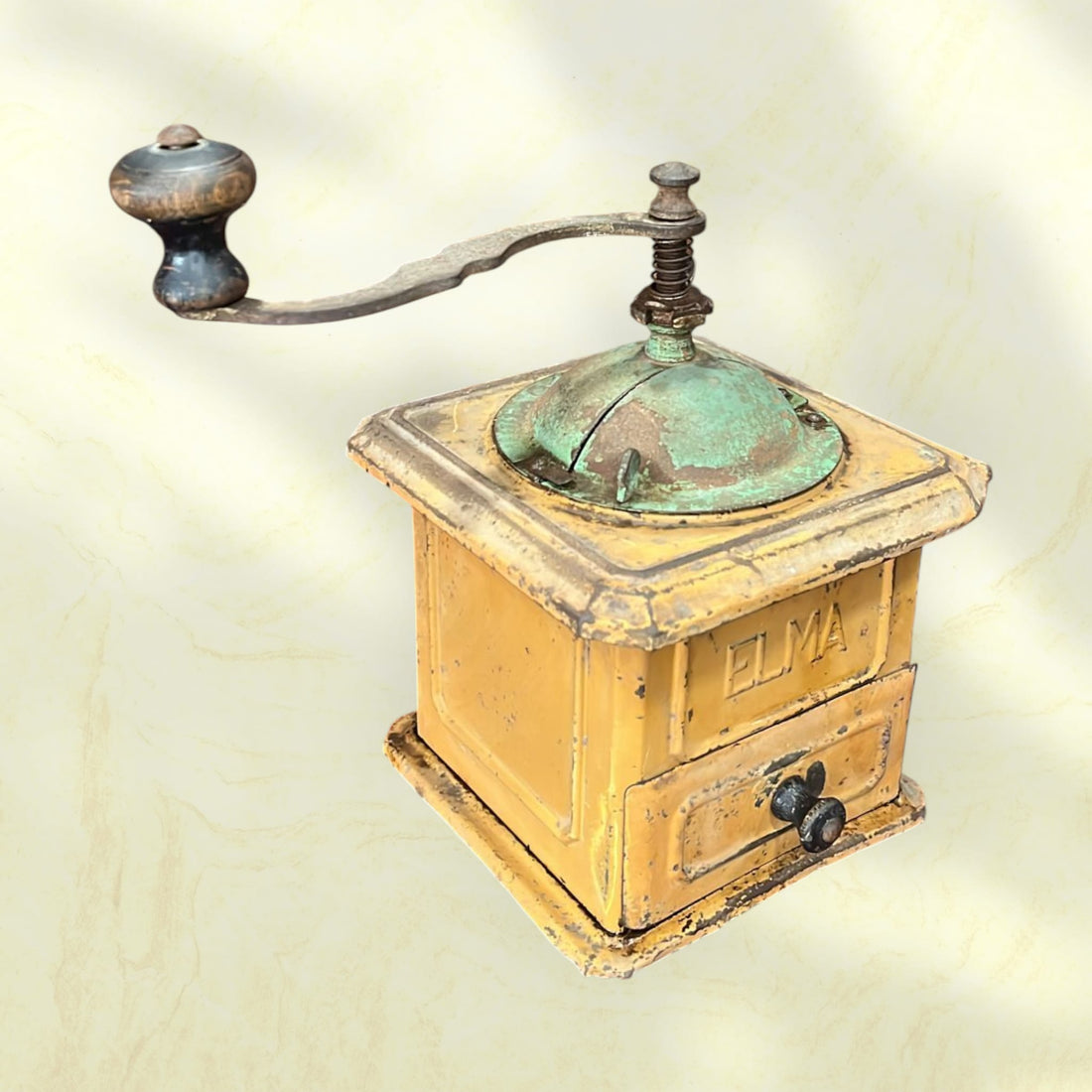 Molinillo de café Elma antiguo de hierro fundido, pieza única con acabado envejecido en color amarillo y detalles en verde oxidado. Ideal para decoración vintage en cocina o sala.