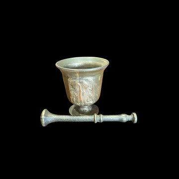 Mortero de bronce antiguo con relieve decorativo y maja incluida.