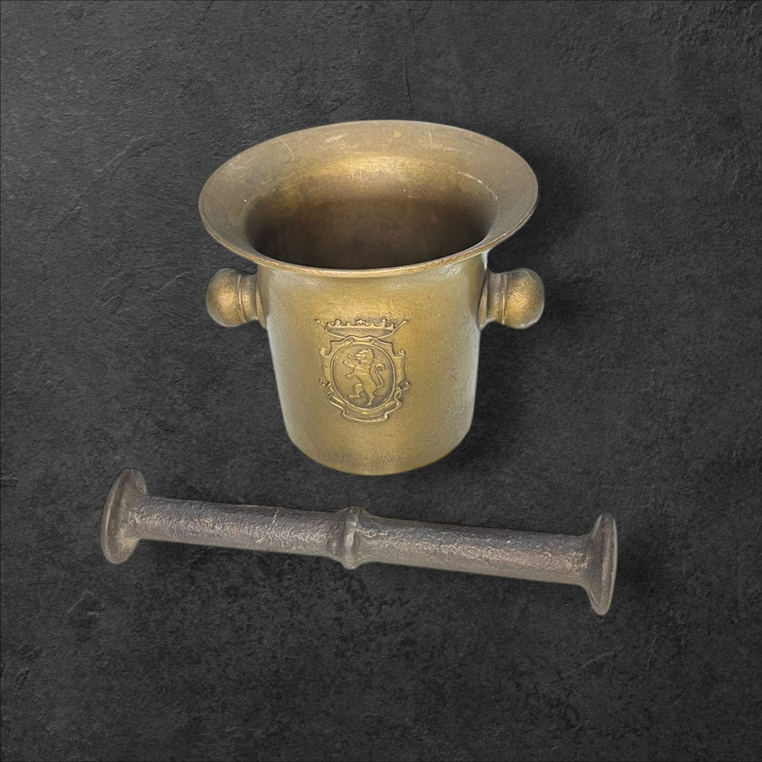 Mortero de farmacia en bronce antiguo con escudo grabado, ideal para decoración vintage en hogar o farmacia. Elegancia y distinción clásica.