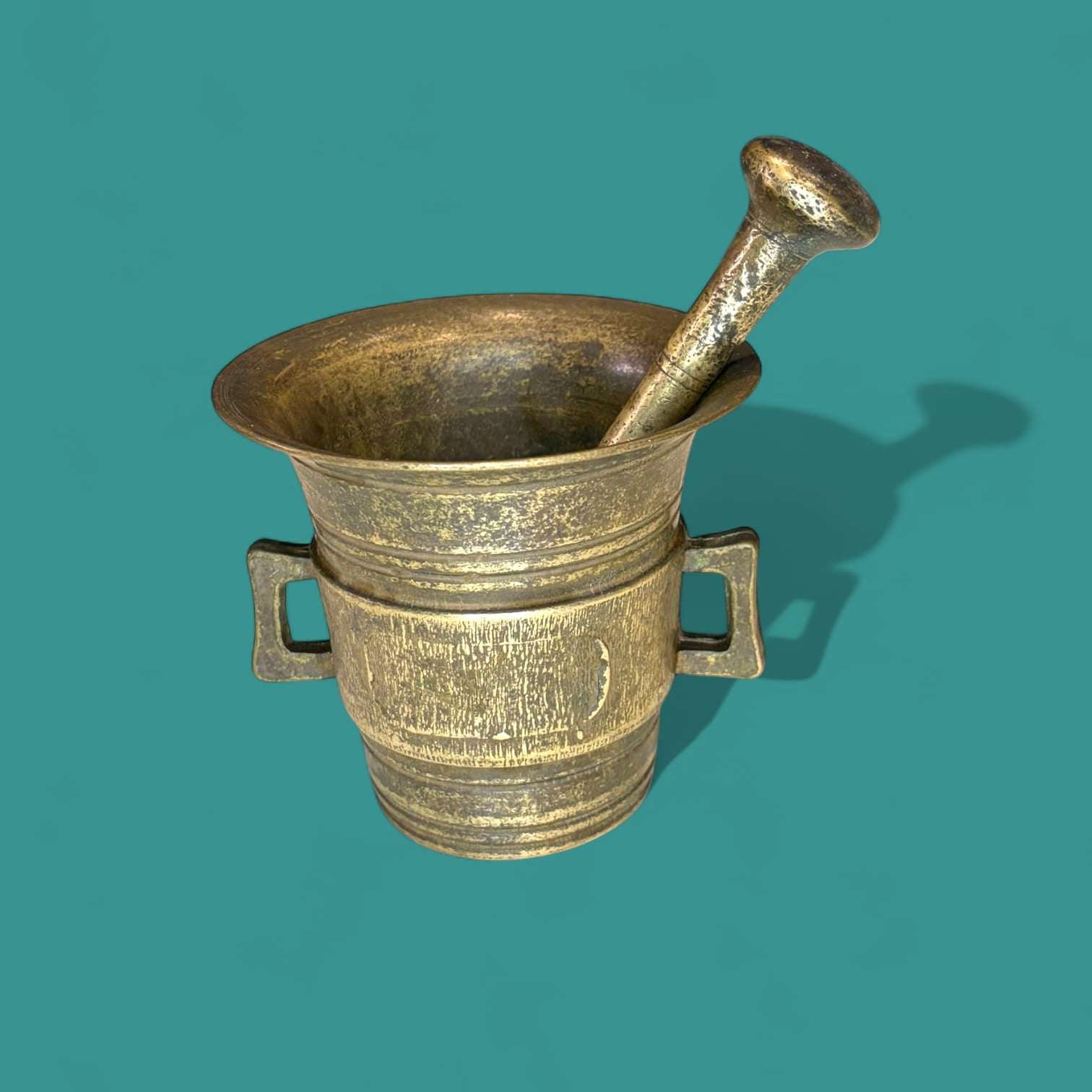Mortero antiguo de bronce con maja original y único, con asas laterales y acabado envejecido, ideal para decoración vintage en el hogar.