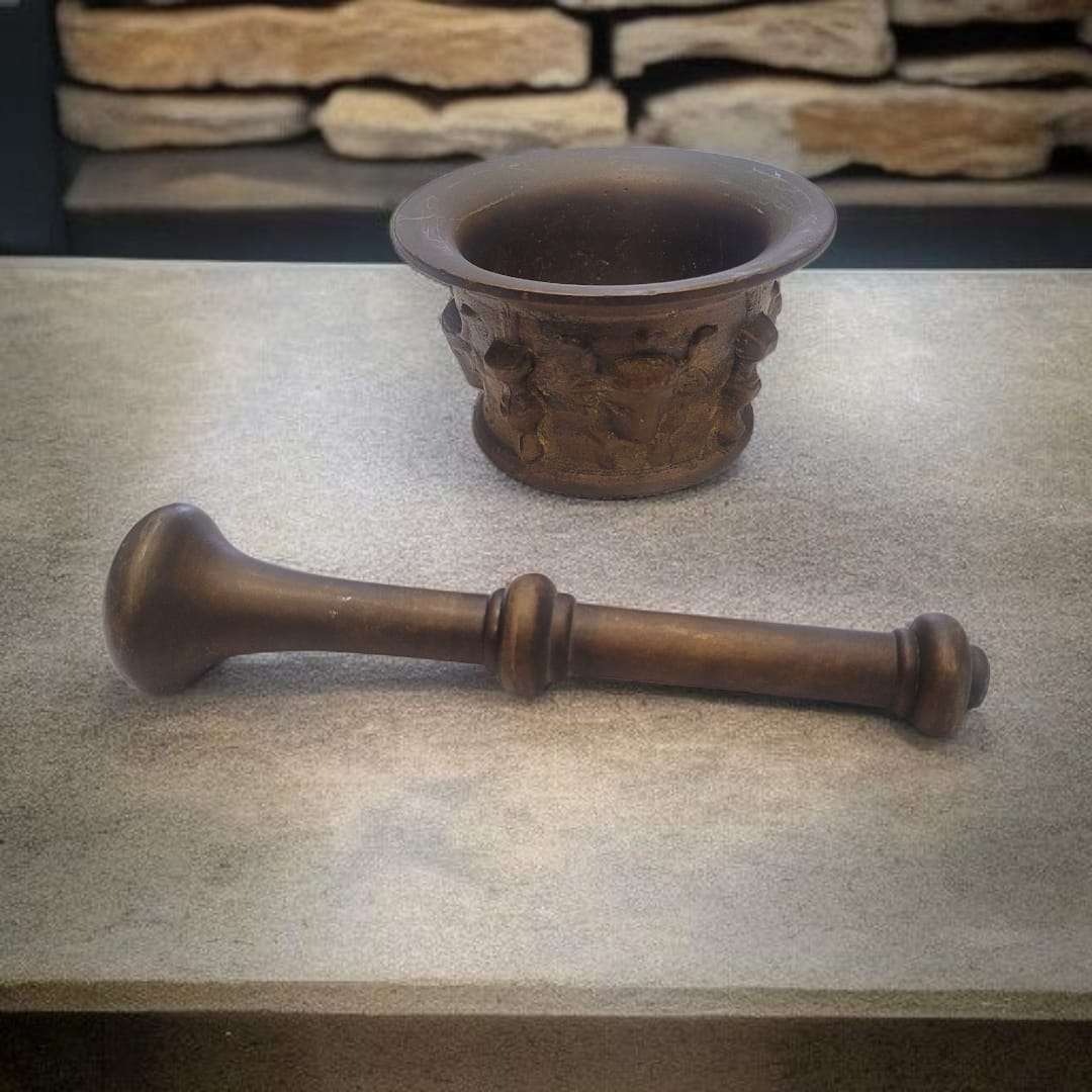 Mortero de bronce antiguo con maja artesanal sobre piedra rústica. Ideal para cocina tradicional o decoración vintage de hogar.