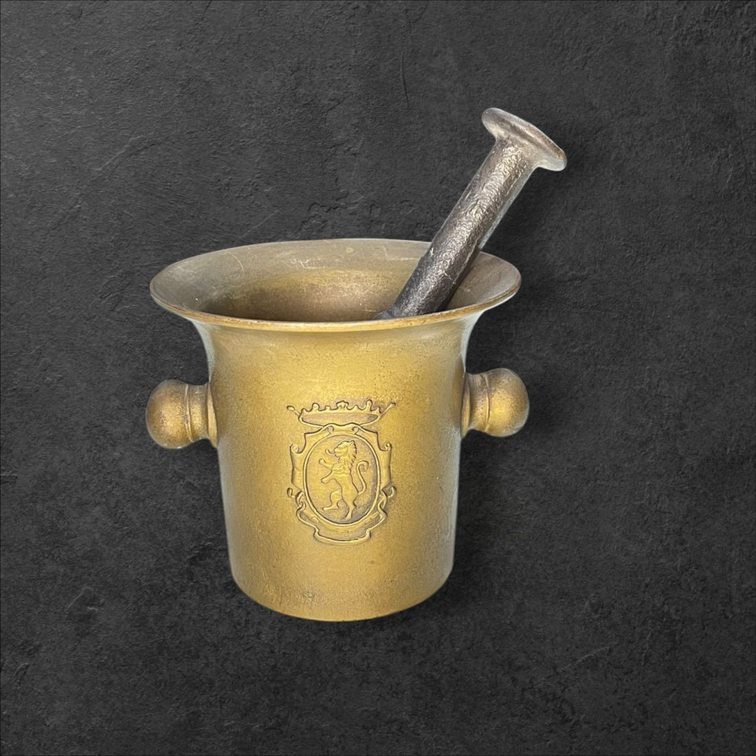 Mortero de farmacia en bronce antiguo con escudo grabado, ideal para decoración vintage en hogar o farmacia. Elegancia y distinción clásica.