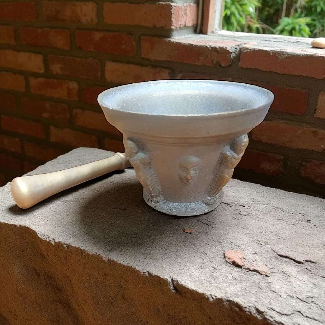 Mortero antiguo de bronce con relieves y maja única, ideal para decoración rústica en cocina o jardín. Diseño clásico con figuras en relieve.