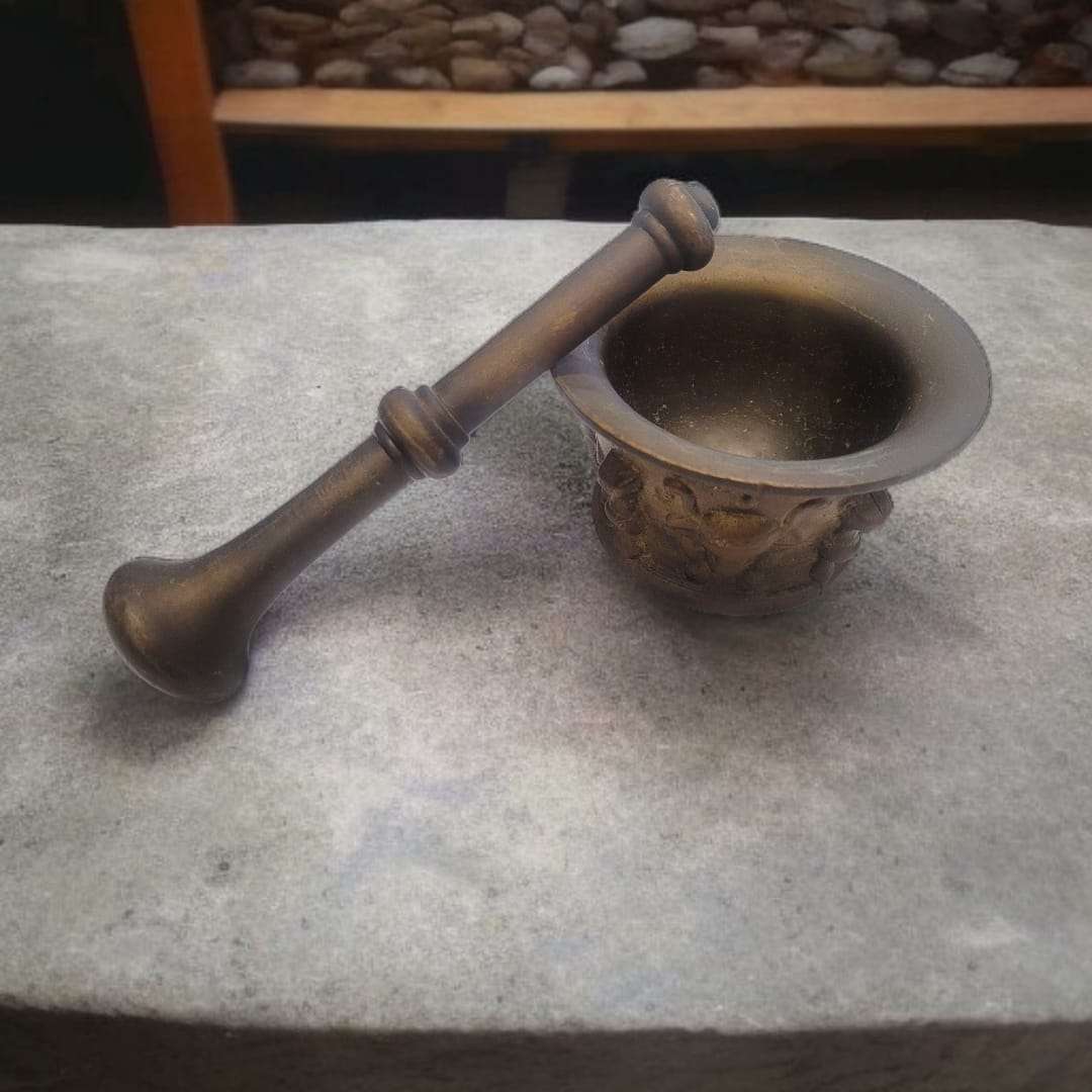 Conjunto de mortero de bronce antiguo y maja sobre superficie de piedra. Artesanía decorativa para amantes del estilo vintage.