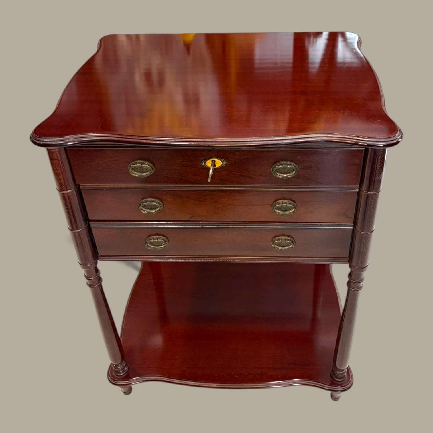 Mueble cubertero de madera con tres cajones y llave, acabado brillante y detalles clásicos, ideal para decoración de interiores elegantes.