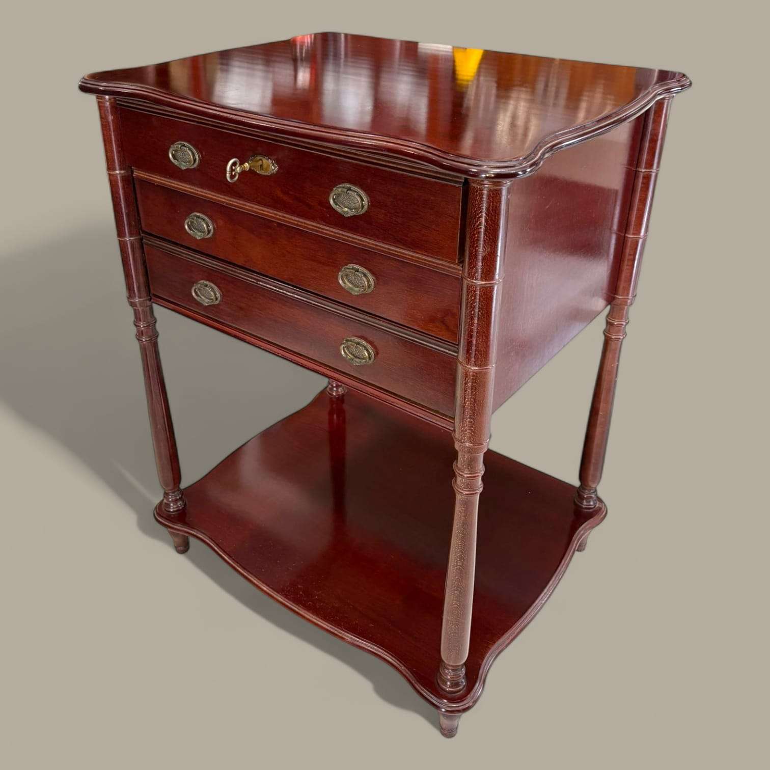 Mueble cubertero de madera con tres cajones, llave y acabado brillante, ideal para decoración elegante en el hogar. Diseño clásico con patas torneadas.