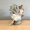 Escultura de porcelana Lladró Day Dream, mujer sentada junto a árbol en flor.