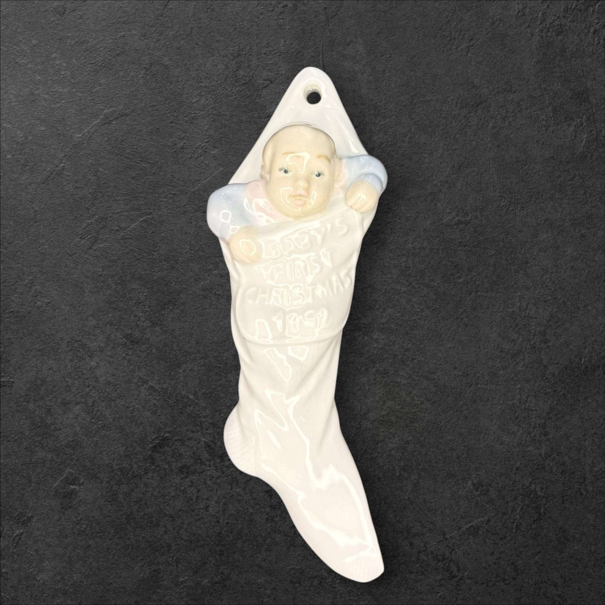 Figura de porcelana Lladró con bebé en calcetín navideño blanco. Diseño exclusivo para celebrar la primera Navidad del bebé.