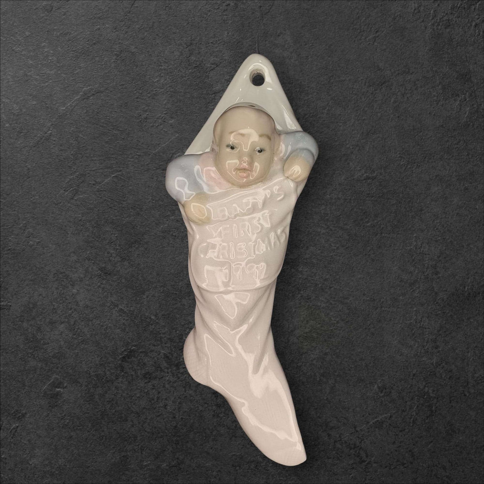 Lladró 'La primera Navidad del bebé', figura de porcelana con bebé en calcetín con inscripción. Decoración emotiva para el hogar.