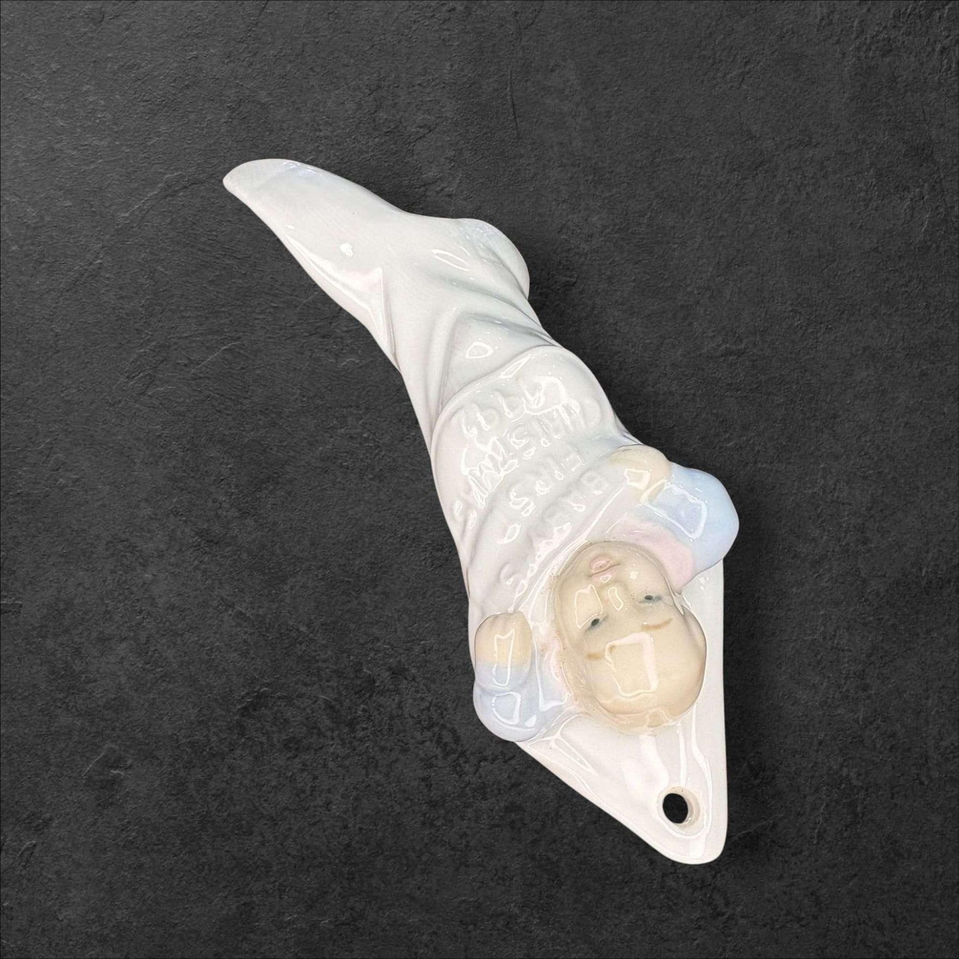 Decoración navideña de porcelana Lladró con bebé envuelto en calcetín blanco y azul. Diseño exclusivo 'La primera Navidad del bebé'.