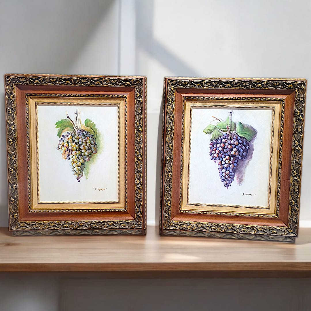 Pareja de óleos con racimos de uvas, firmados por Manuel Ruiz Ortega. Elegantes marcos dorados con detalles ornamentales, ideales para decoración.