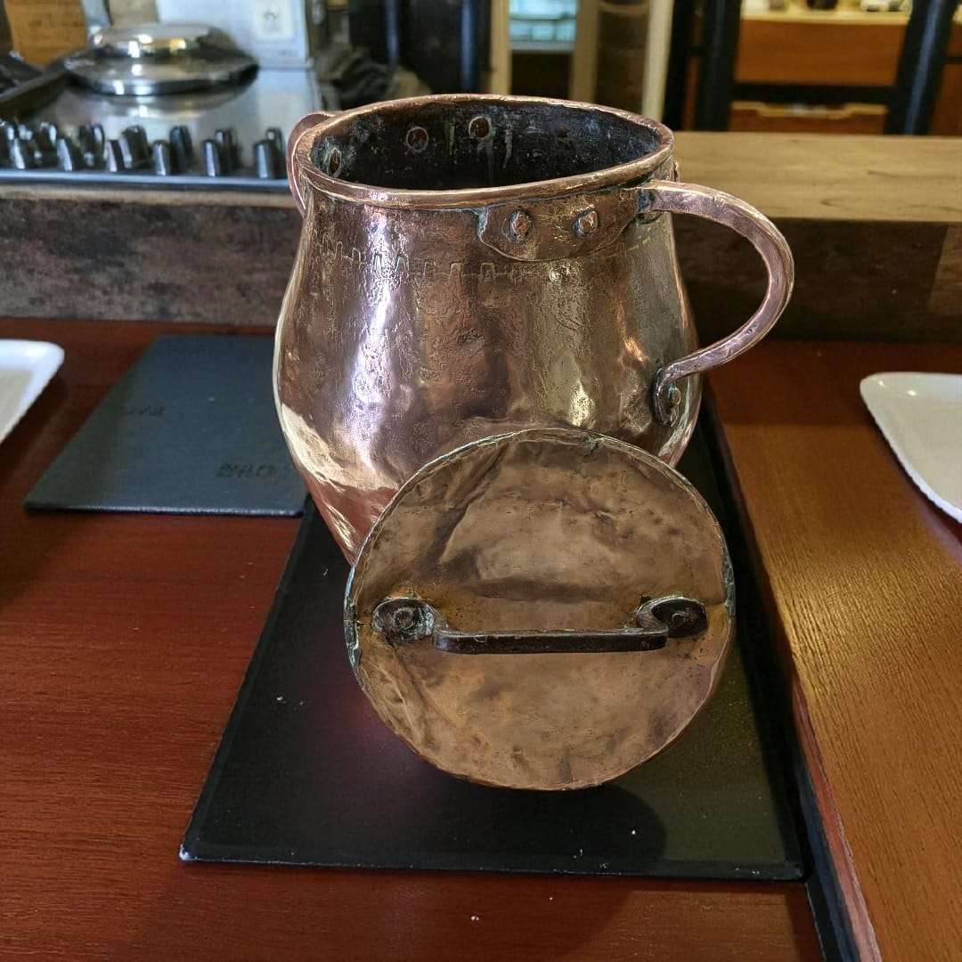 Olla de cobre antigua martilleada con tapa y asas, ideal para decoración rústica en cocina o comedor. Pieza coleccionable de estilo tradicional.