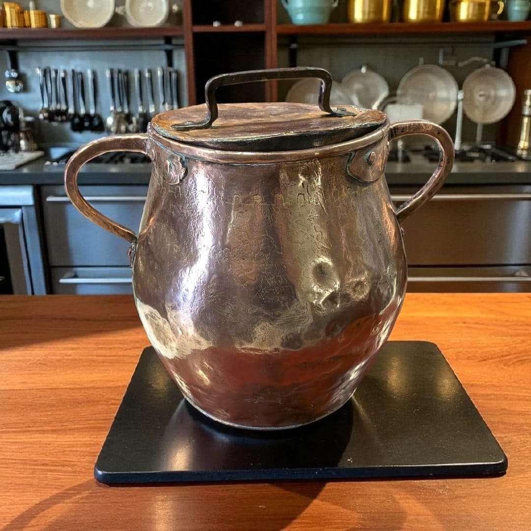 Olla de cobre antigua martilleada con tapa y asas, ideal para decoración rústica en cocinas tradicionales o colecciones vintage.