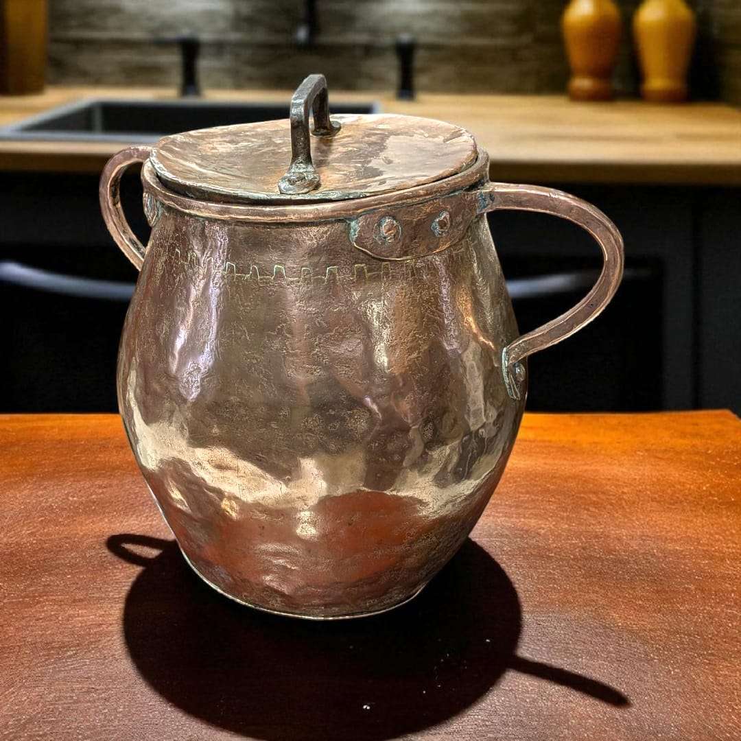 Olla de cobre antigua martilleada con tapa y asas, ideal para decoración rústica de cocina o colección vintage. Acabado artesanal brillante.