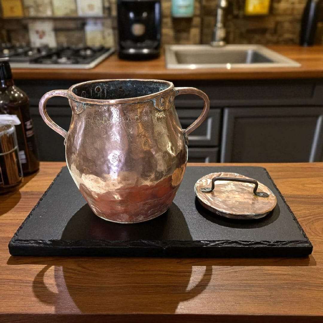 Olla de cobre antigua martilleada con tapa y asas, ideal para decoración rústica de cocina o colección vintage en hogar y jardín.