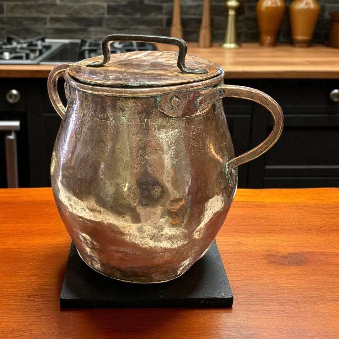 Olla de cobre antigua martilleada con tapa y asas, ideal para decoración rústica en cocinas tradicionales o colecciones vintage.