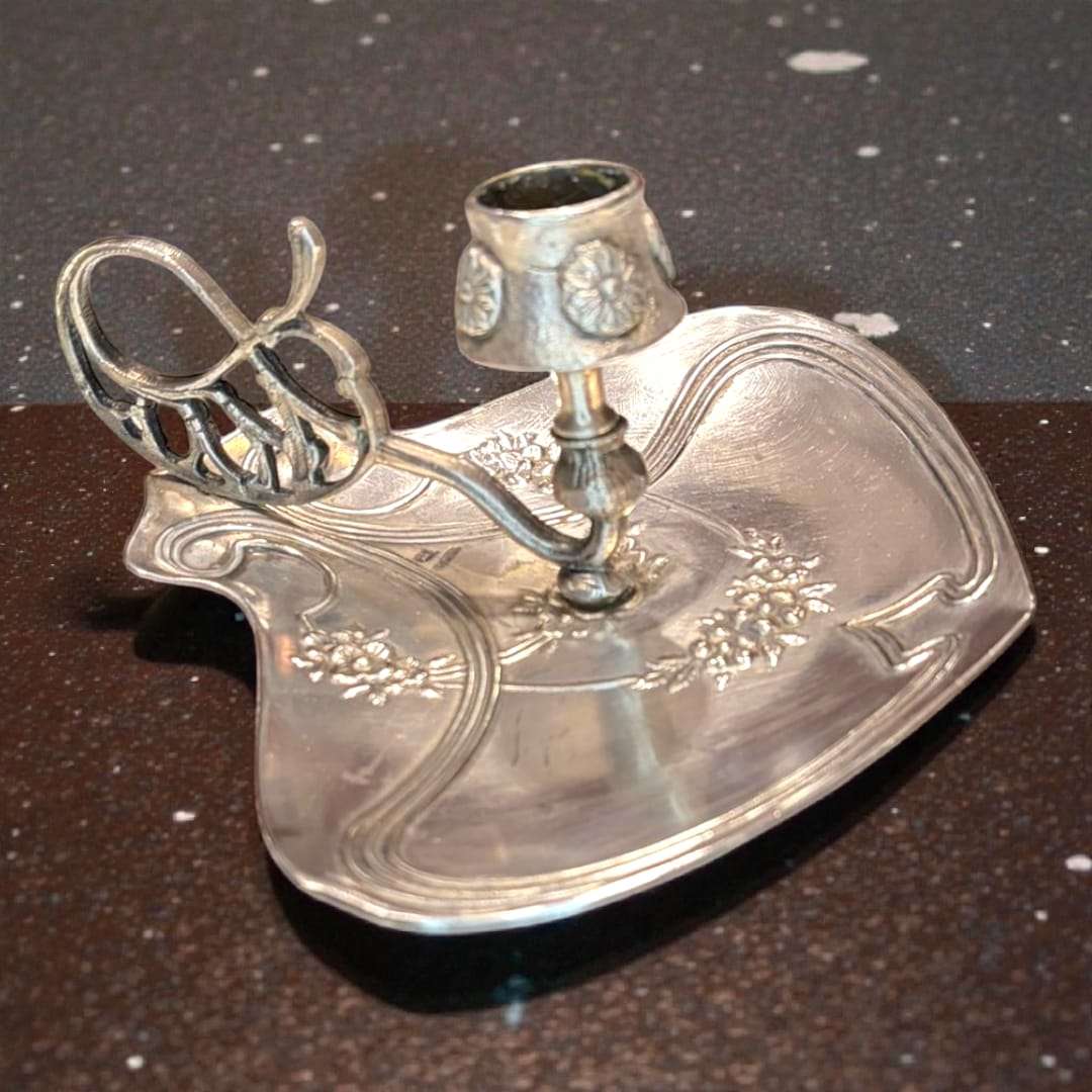 Palmatoria modernista Meneses en metal plateado con relieves florales y asa calada, estilo art nouveau. Decoración exclusiva para el hogar.