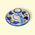 La Palmatoria de cerámica conserva a la perfección su función original, pudiendo usarse como portavelas o como pieza puramente decorativa en ambientes rústicos, vintage o mediterráneos.